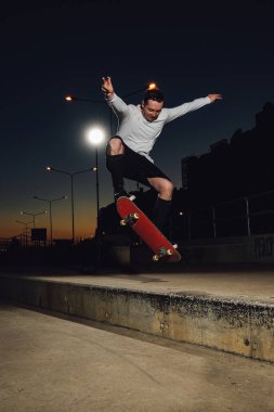 Beyaz günlük giysiler içinde kaykay atlayan profesyonel kaykaycının portresi..