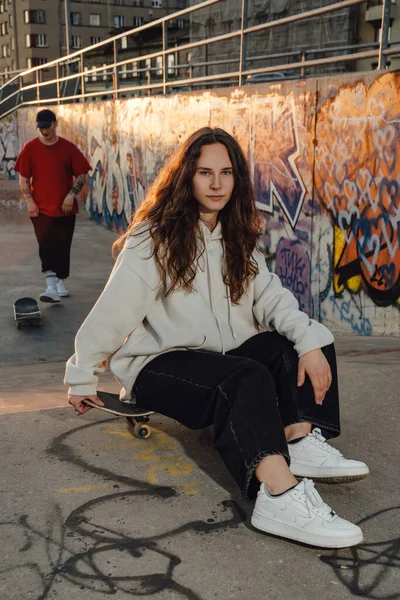 Shot of female skater dressed in casual attire with wavy hairs at skate park.