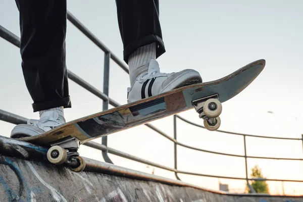 スケートボードにポーズをとる落書きの壁を持つスケートパークでのスポーツマンスケートボーダーの写真 — ストック写真