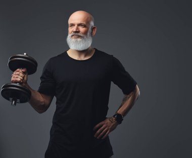 Portrait of muscular old sportsman dressed in sportswear holding dumbbell.