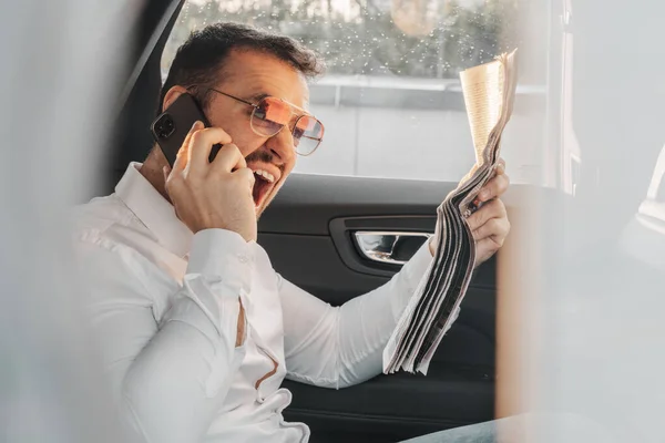 Shot Joyful Businessman Sunglasses Newspaper Talking Phone Sitting His Car — Stock Photo, Image