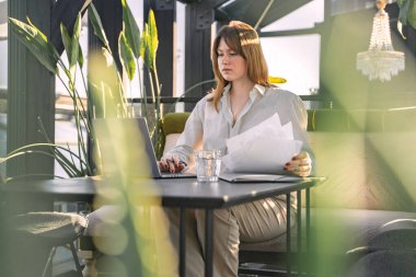 Portrait of professional female executive with documents and computer laptop in office.