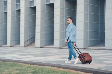 Shot of business person dressed in stylsih suit walking in town with suitcase.