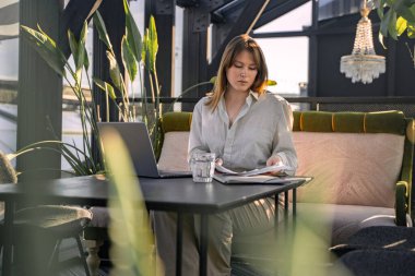 Portrait of professional female executive with documents and computer laptop in office.