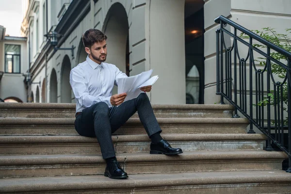 Shot of businessperson dressed in formal attire analyzing documents outdoors in fresh air.
