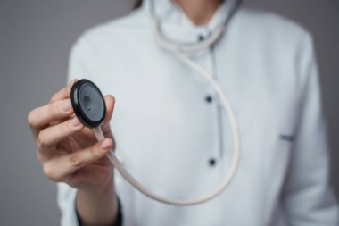 Studio shot of female doctor specialist dressed in labcoat with stethescope isolated on gray.