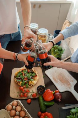 Portrait of four friends celebrating event drinking cola and eating home made pizza.