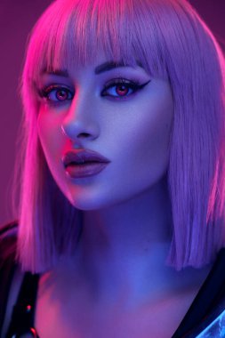 Headshot of cyberpunk woman with lenses and short hairs looking at camera against pink background.