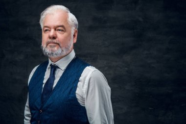 Beyaz gömlek ve yelek giymiş iş adamının karanlık arka planda çekilmiş bir fotoğrafı..