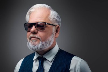 Şık kıyafetler ve güneş gözlüğü takmış, modaya uygun yaşlı bir adamın fotoğrafı..