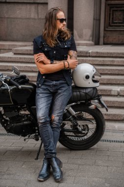 Motosikletle dışarıda poz veren maço bir adamın portresi..