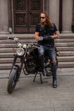 Rock 'çı ve eski moda motosikletine benzeyen trend bir adamın fotoğrafı..