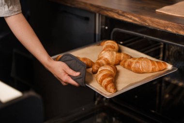 Kafede çalışan kadın barmenin portresi kendi tariflerine göre kruvasan pişiriyor..