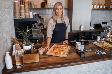 Kahve barında yeni hazırlanmış kruvasanlarla yaşlı bayan barista..
