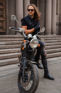 Rock 'çı ve eski moda motosikletine benzeyen trend bir adamın fotoğrafı..