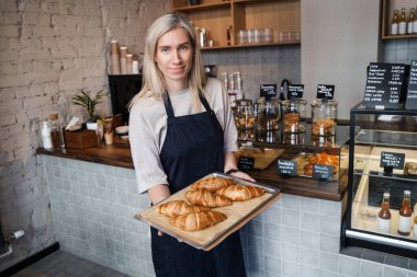 Kahve barında yeni hazırlanmış kruvasanlarla yaşlı bayan barista..