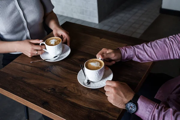 Young couple taking coffee break drinking capuccino in modern coffee bar.