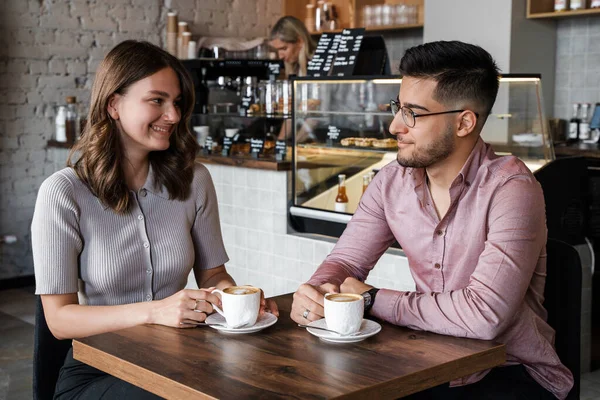 Shot of woman and man talking drinking hot coffee in coffee bar.