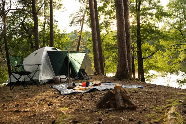 Shot of tourist tent with food and drink on rug in summer wood in daytime.