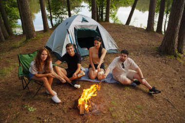Arkadaş yürüyüşçülerin fotoğrafları çadır ve marşmelovlarla birlikte orman yolculuğunda dinleniyorlar..