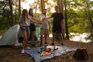 Yazın ormanda kamp yapan ve bira içen dört kişinin fotoğrafı..