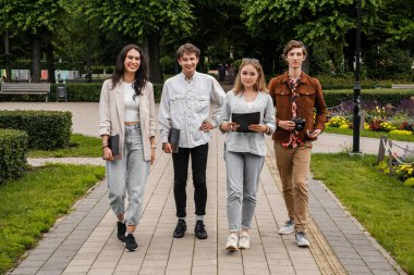 Hafta sonları parkta birlikte yürüyüp eğlenen dört öğrencinin portresi..