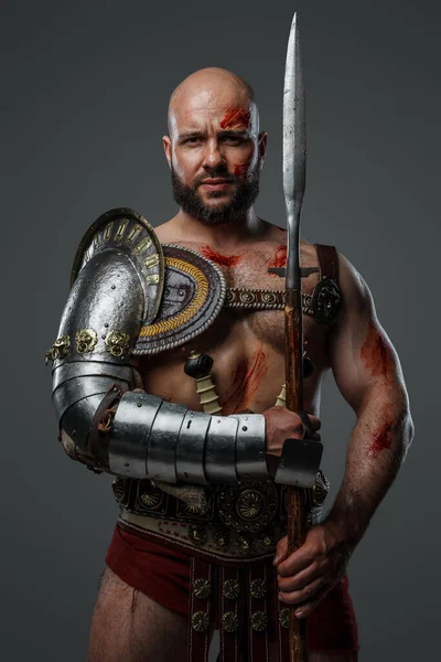 灰色に隔離された長い槍を保持している筋肉質のビルドとハンサムな剣闘士の肖像 — ストック写真