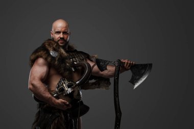 Zırh ve kürk giymiş büyük bir baltayla kaslı antika Viking çekimi..