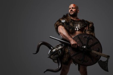Yüzü kanlı, kalkanı ve baltası gri renkli vahşi Viking 'in stüdyo fotoğrafı..