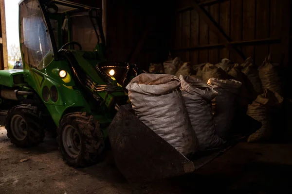 Strzał Zielonego Ciągnika Transportującego Worki Ziemniaków Hangarze Gospodarstwa — Zdjęcie stockowe