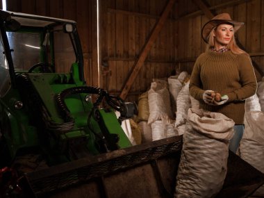 Profesyonel kadın çiftçinin portresi hangarda patates torbalarını boşaltıyor..
