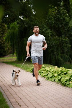 Yazın köpeğiyle koşan neşeli bir sporcunun portresi..