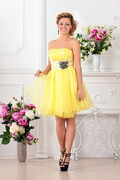 Beautiful woman in yellow dress in luxury studio. — Stock Photo, Image