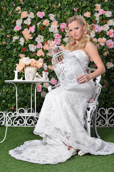 Mooie vrouw in trouwjurk in tuin met bloemen. — Stockfoto