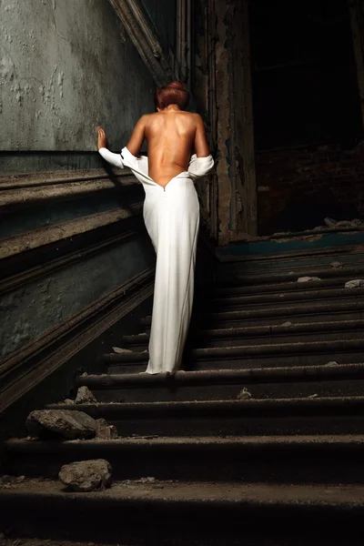 Krásná žena v bílých šatech s nahou zpět v paláci. — Stock fotografie