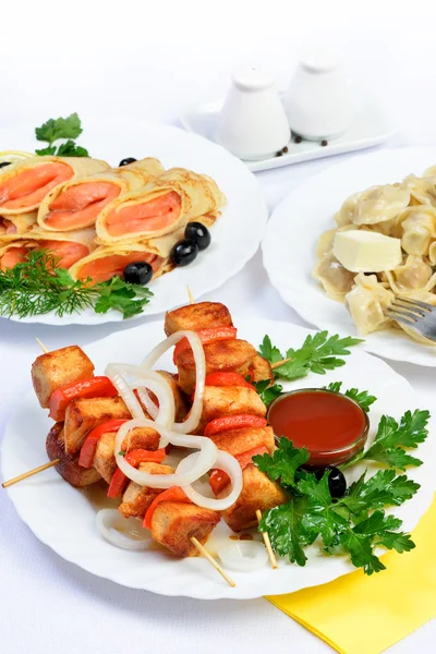 White table with food of meat, salmon rolls and dumplings. — Stock Photo, Image