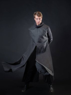 Kırmızı ışın kılıçlı bir kötü adam, uzun cüppeli genç bir adam dövüşüyor.,