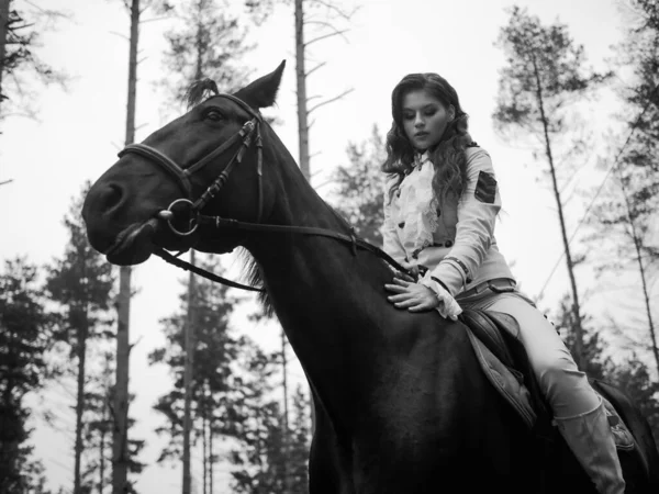 Una joven hermosa jinete morena en un elegante traje retro montando un caballo negro —  Fotos de Stock