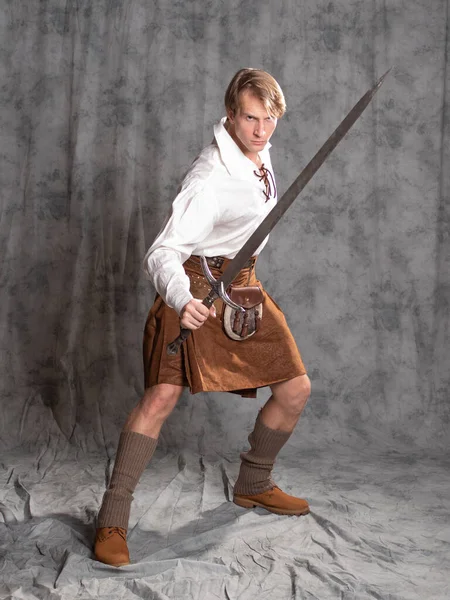 Молодой человек в кожаном килте и белой кружевной блузке. Шотландский рыцарь — стоковое фото