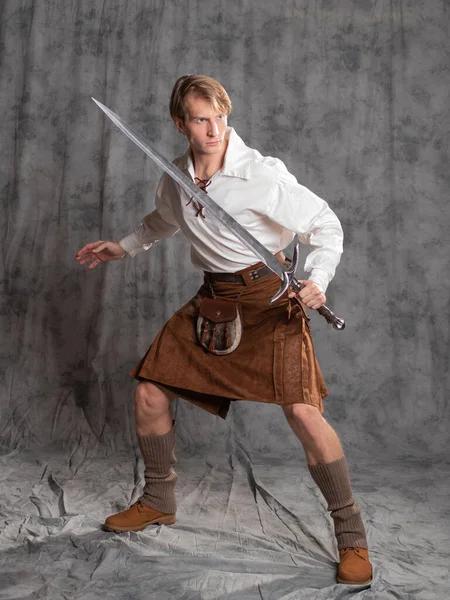 Ein junger Mann in Lederkilt und weißer Schnürbluse. Ein schottischer Ritter — Stockfoto