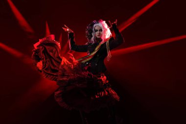 Gösterinin yıldızı, podyumda kırmızı ışıkta şık bir kadın kahraman.