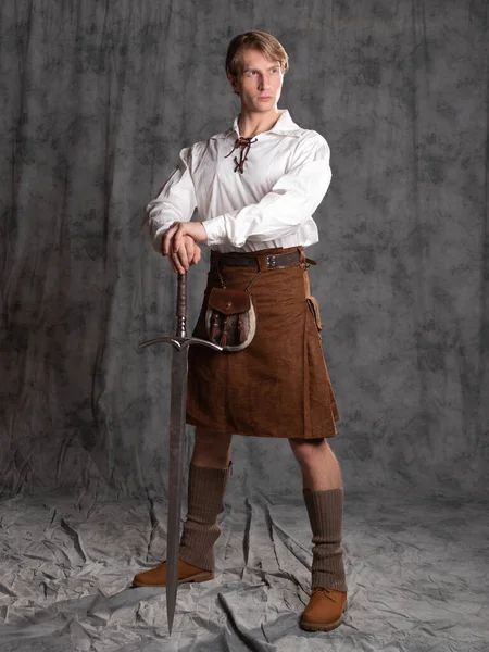 Молодой человек в кожаном килте и белой кружевной блузке. Шотландский рыцарь — стоковое фото