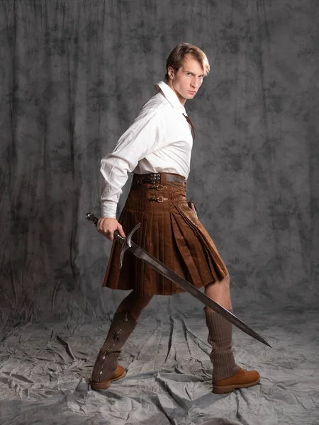 A young man in a leather kilt and a white lace-up blouse. A Scottish knight — Stock Photo, Image