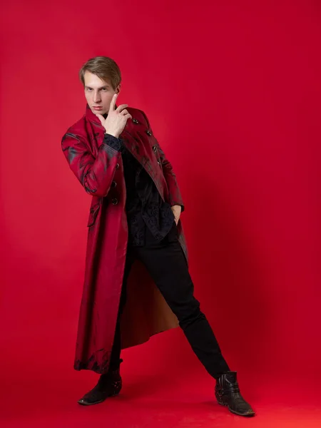 Un jeune homme scandaleux dans un manteau rouge audacieux dans un style noir vintage, — Photo