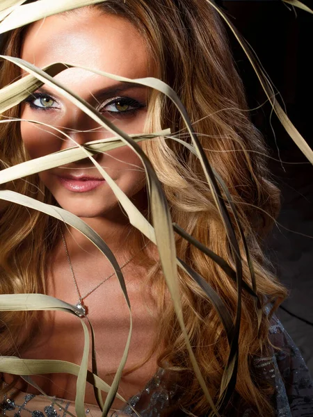 Beautiful young blonde with long curls, portrait in the shade of a palm branch. Royalty Free Stock Photos