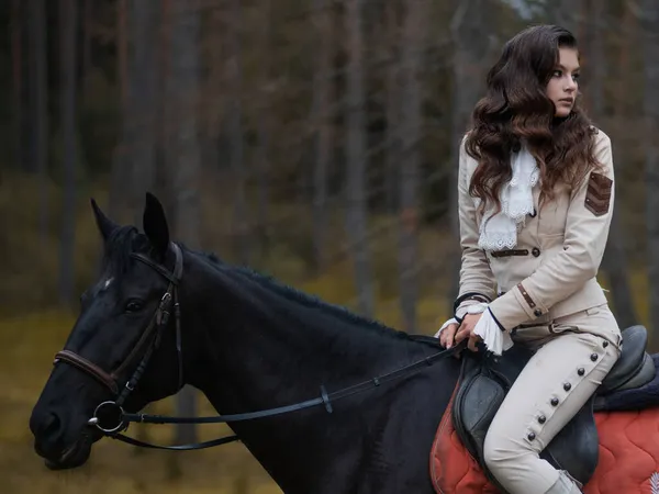 Młoda piękna brunetka jeździec w eleganckim garniturze retro jazda na czarnym koniu — Zdjęcie stockowe