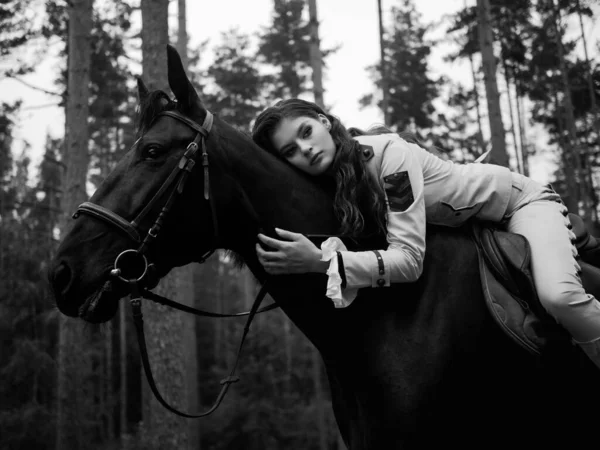 Una joven hermosa jinete morena en un elegante traje retro montando un caballo negro —  Fotos de Stock