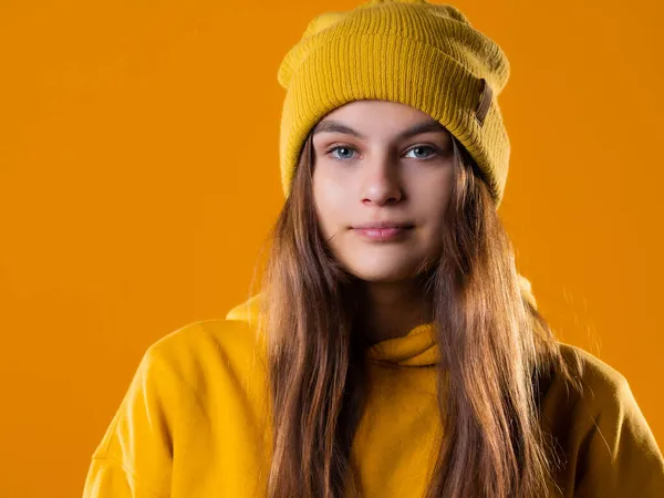 Elegante joven morena alegre en una sudadera con capucha amarilla y sombrero en un amarillo — Foto de Stock