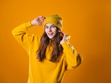 Sarı kapüşonlu ve şapkalı şık, neşeli bir esmer.