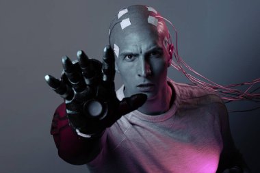 Kafası kabloya dolanmış genç bir adam ve robot bir kol.,